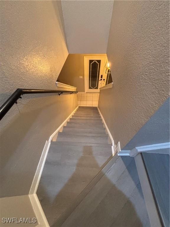 2864 Blossom Ct, Naples, FL 34120 - stairs featuring a textured wall, wood finished floors, and lofted ceiling