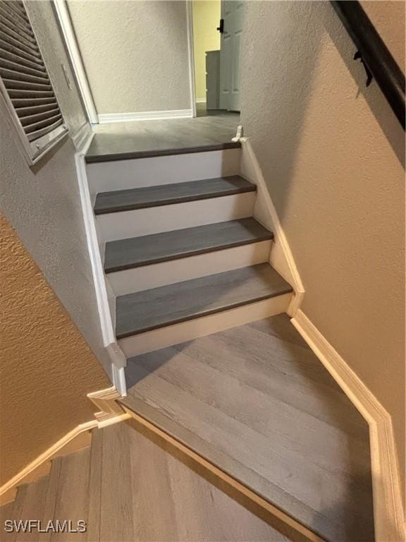 2864 Blossom Ct, Naples, FL 34120 - staircase with a textured wall and wood finished floors