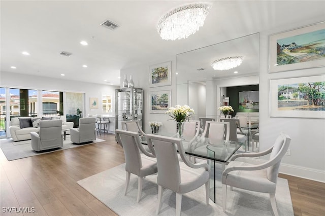 dining area with light wood-type flooring and a chandelier