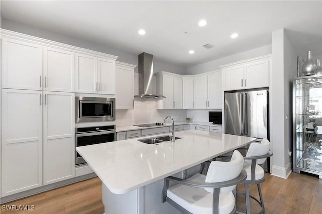 21490 Strada Nuova Cir Unit D307, Estero, FL 33928 - kitchen with appliances with stainless steel finishes, wall chimney exhaust hood, a sink, a center island with sink, and light countertops