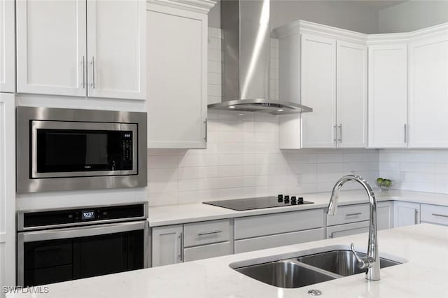 kitchen featuring white cabinets, sink, wall chimney exhaust hood, stainless steel appliances, and decorative backsplash