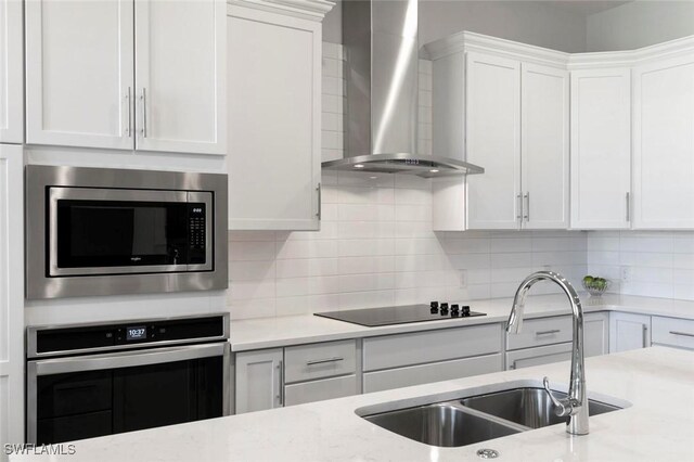21490 Strada Nuova Cir Unit D307, Estero, FL 33928 - kitchen with stainless steel appliances, wall chimney range hood, a sink, white cabinetry, and backsplash