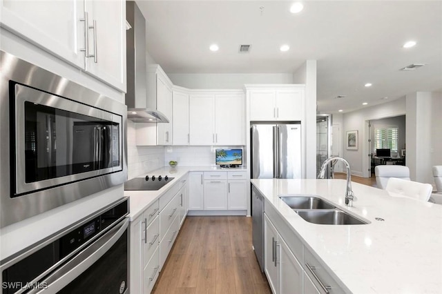 21490 Strada Nuova Cir Unit D307, Estero, FL 33928 - kitchen with stainless steel appliances, wall chimney exhaust hood, a sink, white cabinets, and decorative backsplash