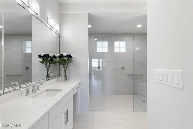 bathroom with tile patterned flooring, walk in shower, a wealth of natural light, and vanity