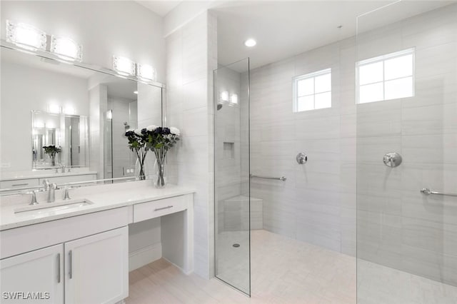 bathroom with a tile shower and vanity