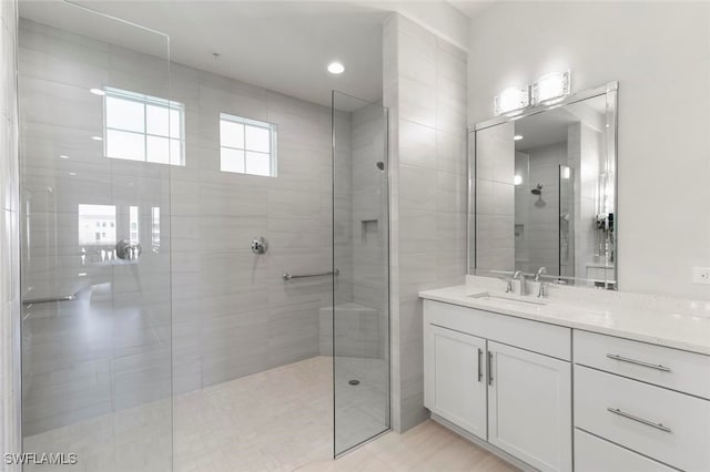 bathroom featuring tiled shower and vanity