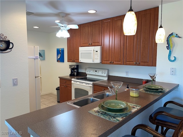 kitchen with sink, white appliances, a breakfast bar, decorative light fixtures, and kitchen peninsula