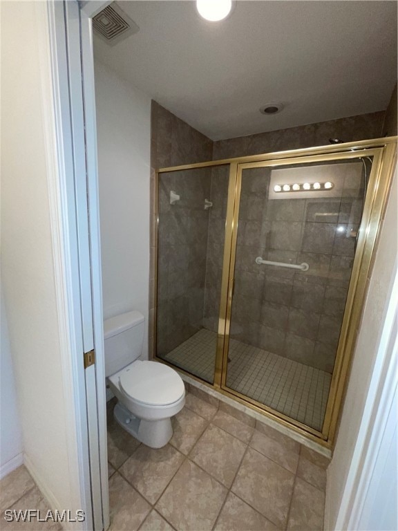 bathroom with an enclosed shower, tile patterned floors, and toilet