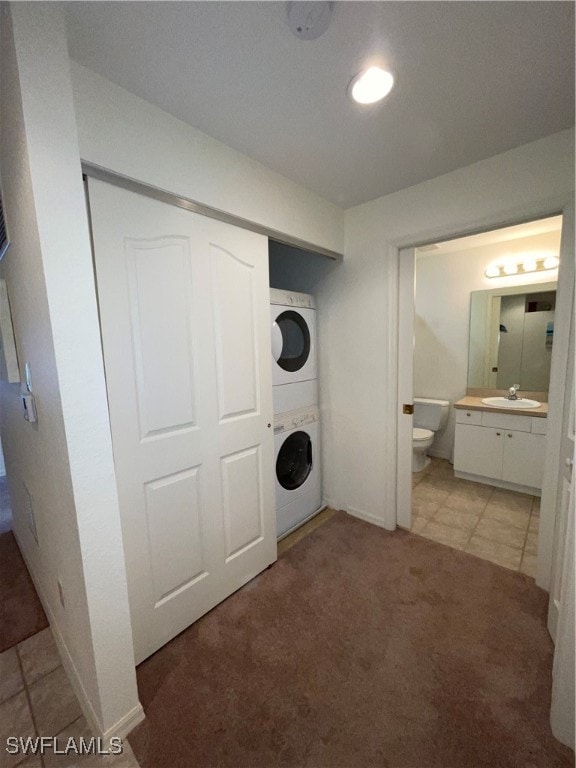 clothes washing area with stacked washer / drying machine, light colored carpet, and sink