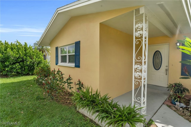 view of exterior entry with a yard