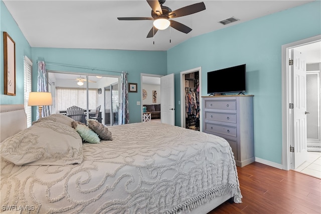 bedroom with ceiling fan, a spacious closet, a closet, lofted ceiling, and hardwood / wood-style flooring