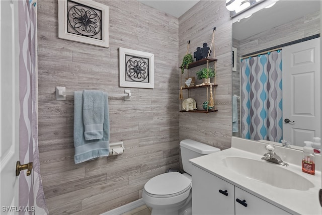 bathroom featuring vanity, wood walls, toilet, and tile walls