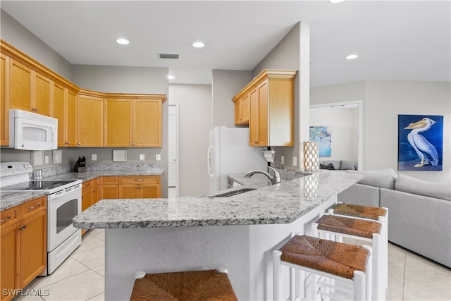 kitchen with white appliances, light tile patterned flooring, a breakfast bar area, and sink