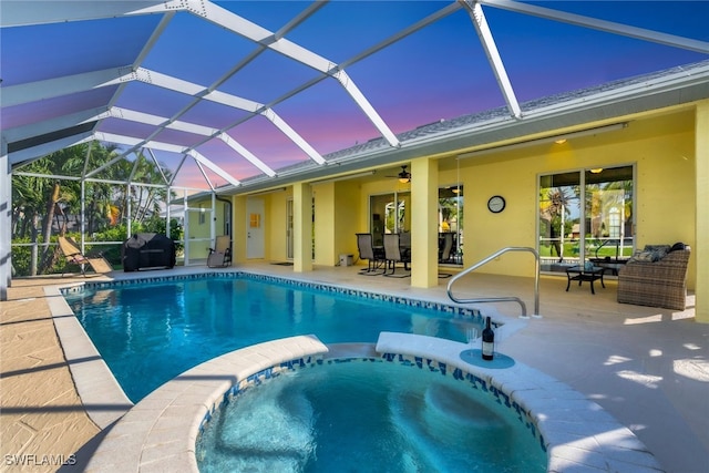 pool at dusk featuring an in ground hot tub, outdoor lounge area, glass enclosure, and a patio