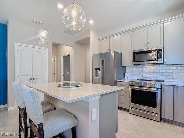 kitchen featuring gray cabinets, a kitchen island, and appliances with stainless steel finishes