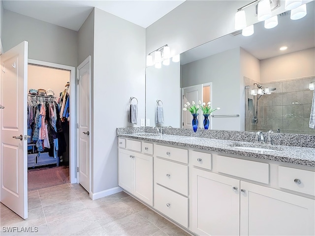 bathroom featuring a tile shower, vanity, and tile patterned floors