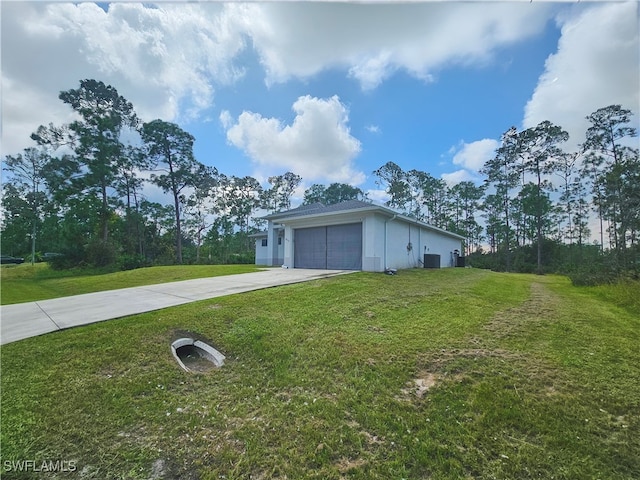 view of side of property with central air condition unit, a yard, and a garage