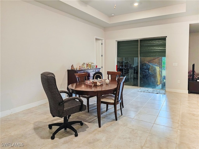 dining space with light tile patterned floors and a tray ceiling