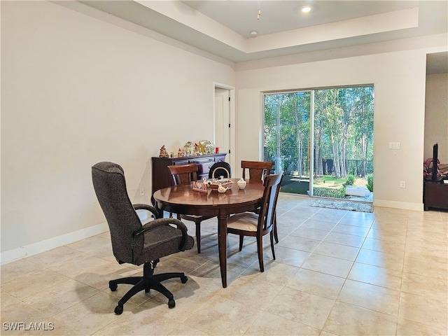 dining space featuring a tray ceiling and light tile patterned floors