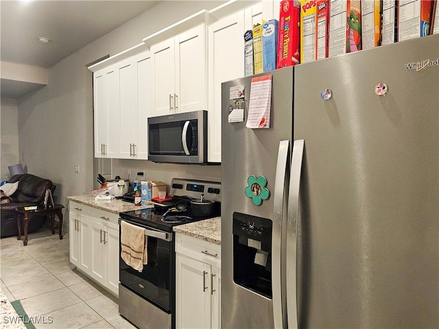 kitchen featuring light stone counters, appliances with stainless steel finishes, light tile patterned floors, and white cabinets