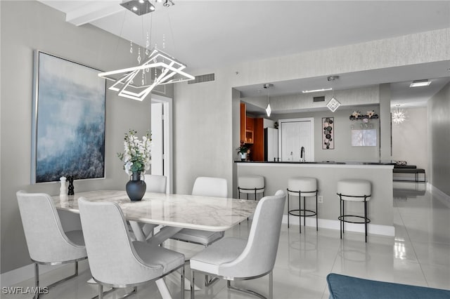 dining space featuring a chandelier, light tile patterned floors, and sink