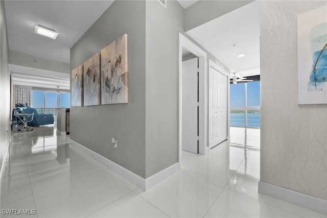 corridor with a wall of windows, light tile patterned floors, and a water view