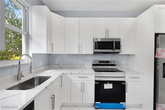 kitchen with fridge, white cabinetry, sink, and range with electric cooktop