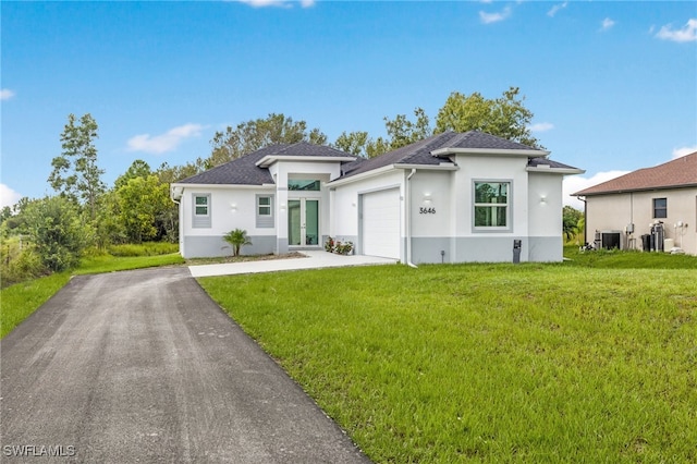 view of front of house featuring a garage, central AC unit, and a front lawn