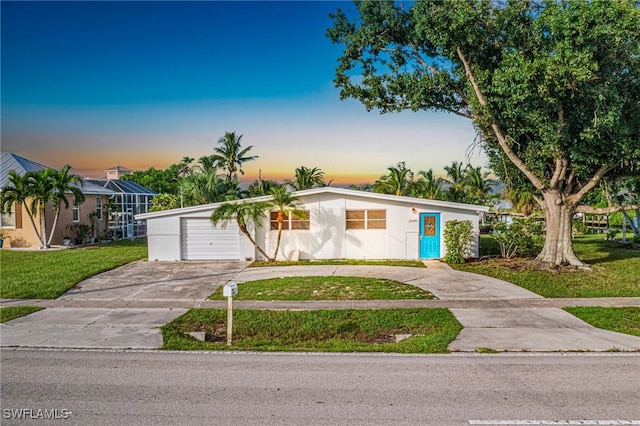 view of front of property featuring a garage, concrete driveway, a front yard, and stucco siding