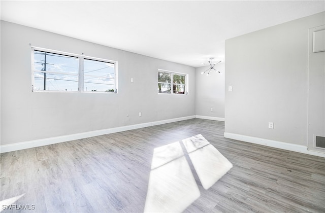 unfurnished room featuring hardwood / wood-style flooring, a chandelier, and a healthy amount of sunlight