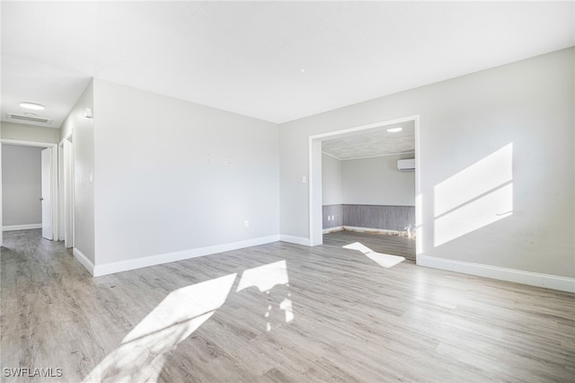 spare room with a wall unit AC and light hardwood / wood-style floors