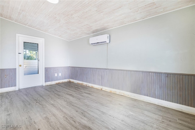 unfurnished room featuring hardwood / wood-style flooring, lofted ceiling, wooden walls, a wall mounted AC, and wooden ceiling