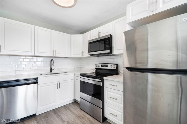 kitchen featuring white cabinets, sink, tasteful backsplash, stainless steel appliances, and light hardwood / wood-style floors