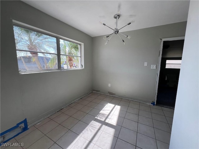 unfurnished room with light tile patterned floors, baseboards, and a notable chandelier