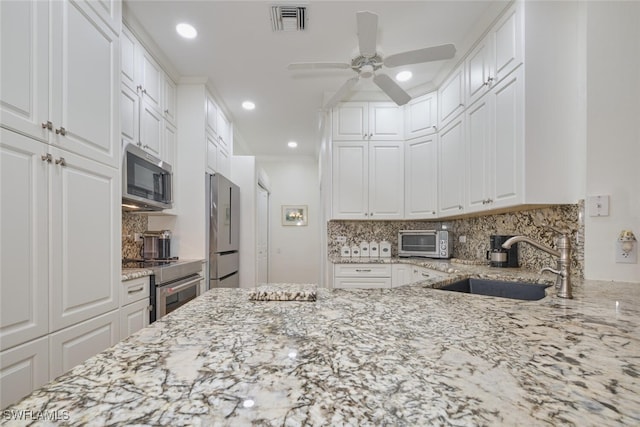 kitchen with white cabinetry, light stone counters, backsplash, stainless steel appliances, and sink