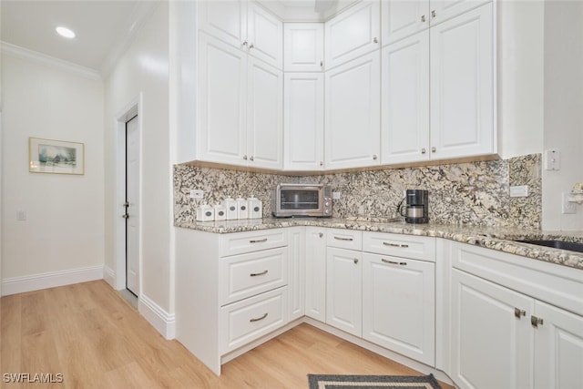 kitchen featuring light wood-type flooring, ornamental molding, and white cabinetry