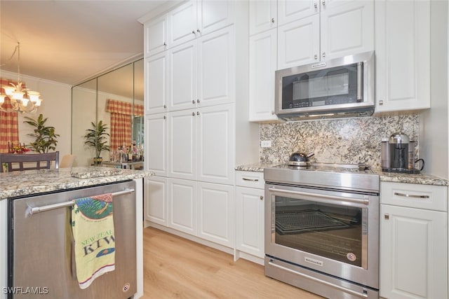 kitchen featuring white cabinets, hanging light fixtures, ornamental molding, stainless steel appliances, and light wood-type flooring