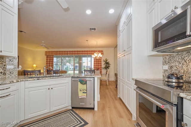 kitchen with sink, white cabinetry, kitchen peninsula, appliances with stainless steel finishes, and crown molding