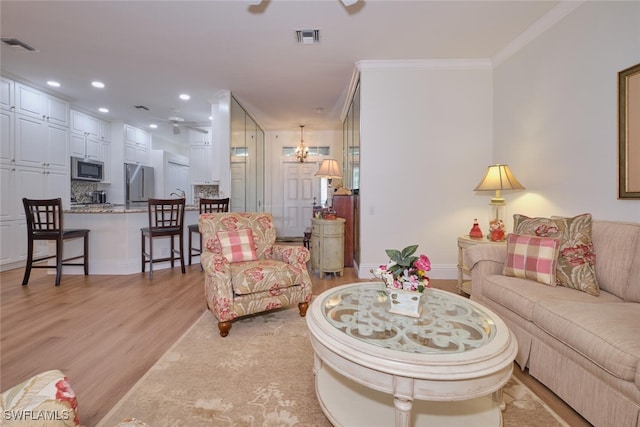 living room with ceiling fan, ornamental molding, and light hardwood / wood-style floors