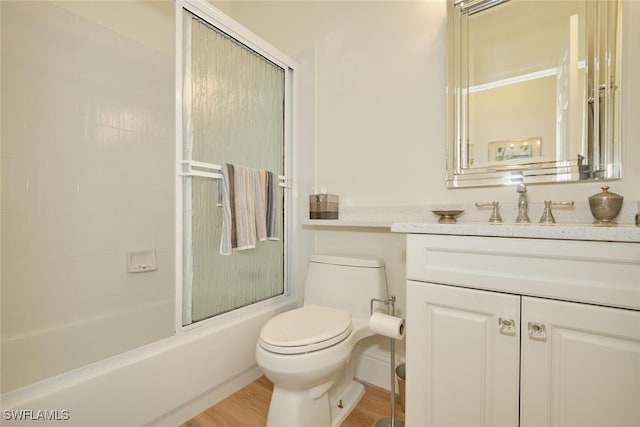 full bathroom featuring vanity, hardwood / wood-style floors, toilet, and combined bath / shower with glass door