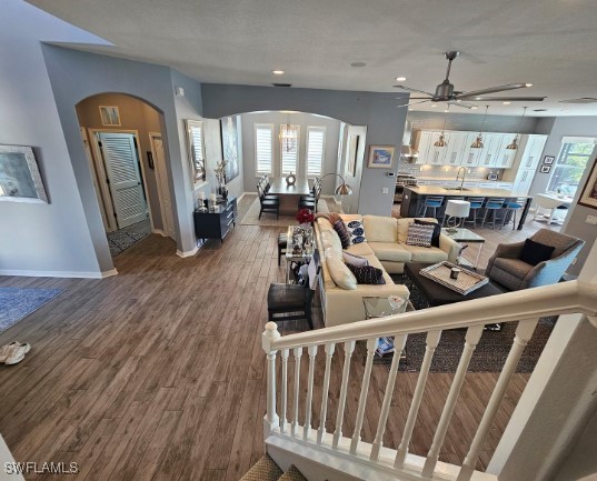 living room featuring ceiling fan with notable chandelier, hardwood / wood-style flooring, and sink