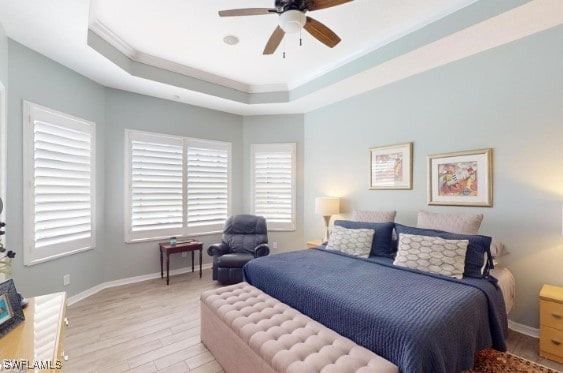 bedroom featuring crown molding, ceiling fan, a raised ceiling, and light hardwood / wood-style flooring