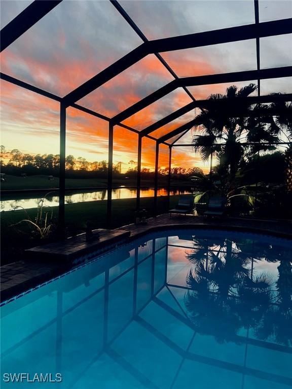 outdoor pool featuring a patio area, glass enclosure, and a water view