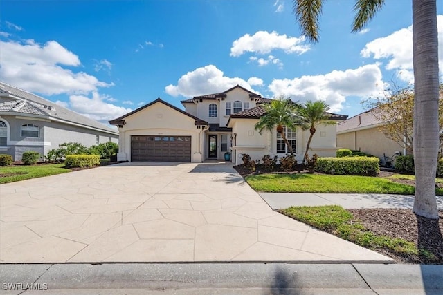 mediterranean / spanish-style house featuring stucco siding, concrete driveway, an attached garage, a tiled roof, and a front lawn