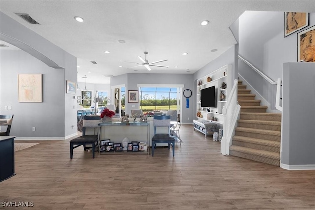 living area featuring baseboards, visible vents, wood finished floors, stairs, and recessed lighting