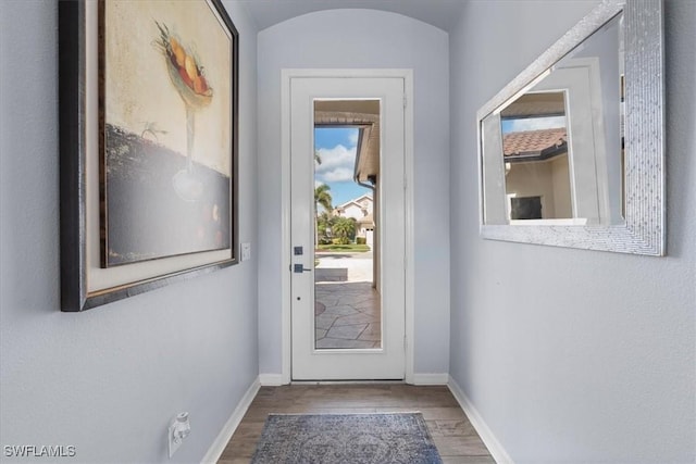 doorway featuring baseboards and wood finished floors