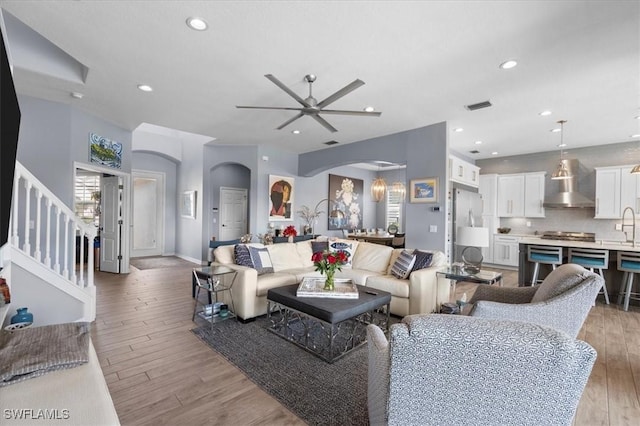 living area featuring light wood finished floors, visible vents, arched walkways, and recessed lighting