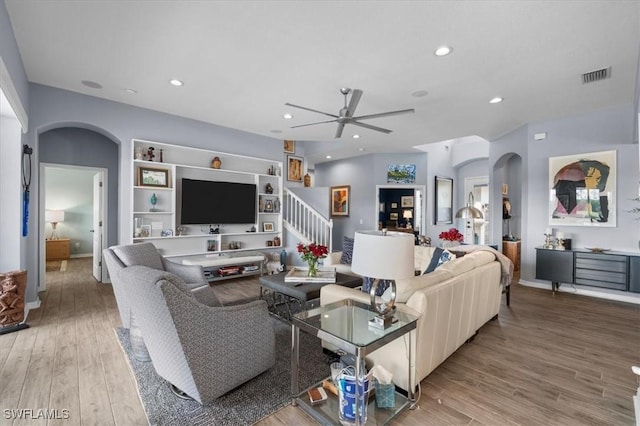 living room featuring light wood finished floors, visible vents, arched walkways, and recessed lighting