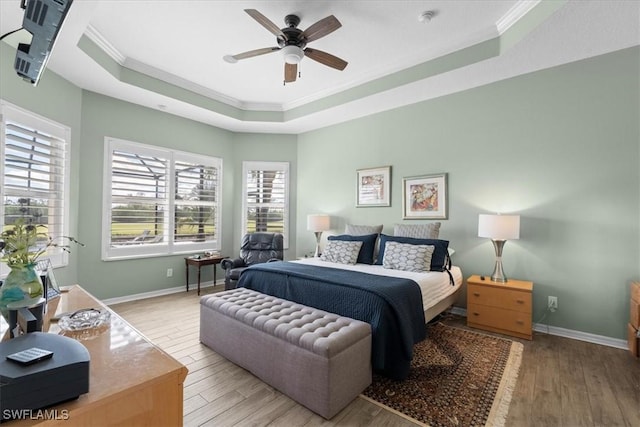 bedroom featuring crown molding, a raised ceiling, light wood-style flooring, a ceiling fan, and baseboards