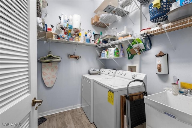 laundry area featuring light wood-type flooring, laundry area, washer and clothes dryer, and a sink